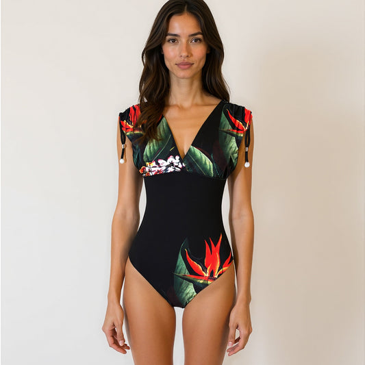 Woman wearing a black one-piece swimsuit with colorful bird of paradise patterns on a black background