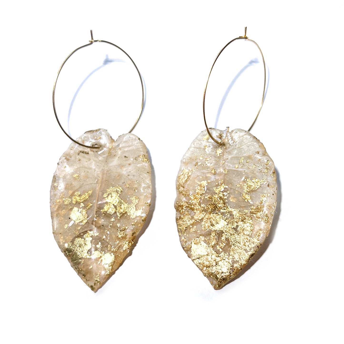 Pair of leaf-shaped earrings with gold flakes on a white background