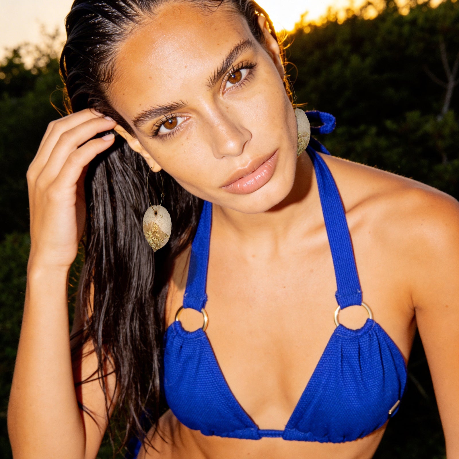 Model wearing Ibiza bright blue bikini and bougainvillea flower petal earrings - detail
