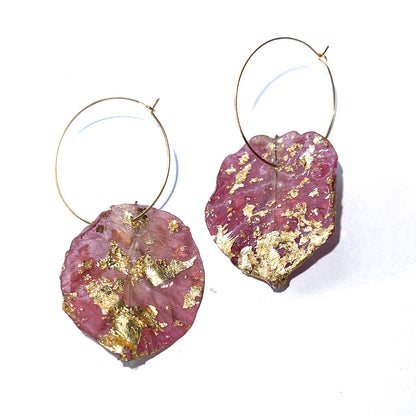 Pink earrings with gold leaf on a white background