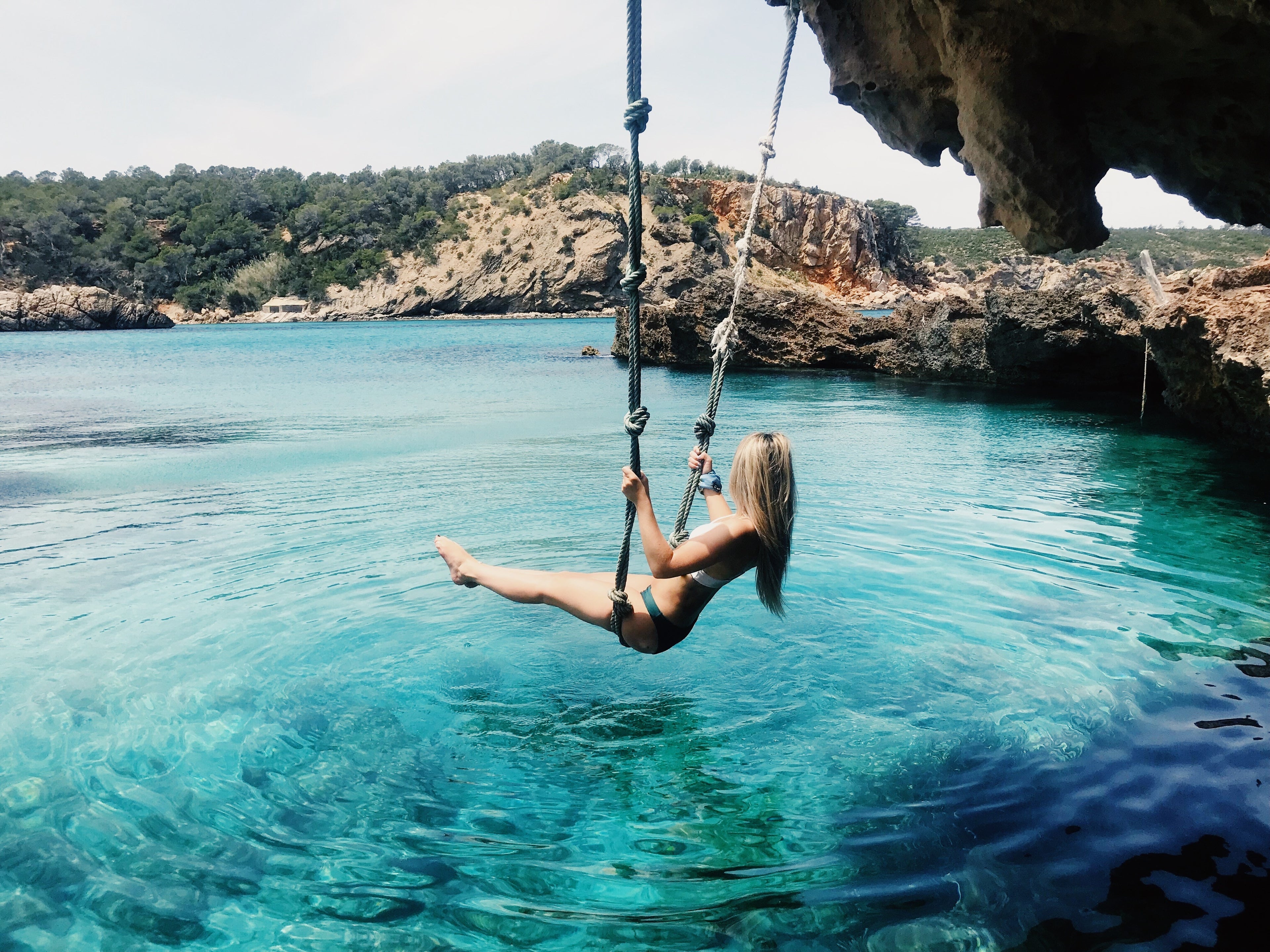 Woman in a swing over Ibiza Bay