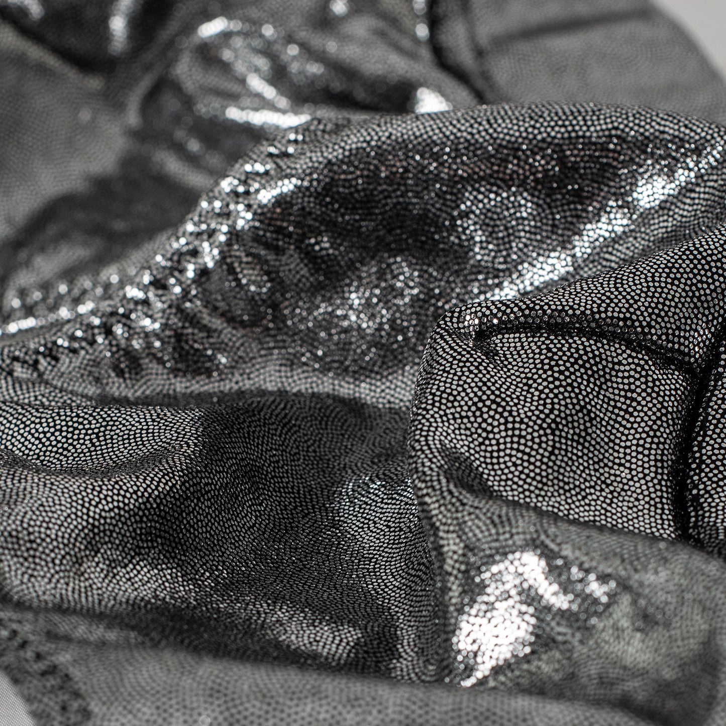 Close-up of a textured fabric with a pattern of raised dots and metallic sheen.